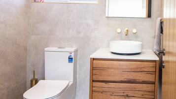 A bathroom with a toilet, a sink, and a wooden cabinet.
