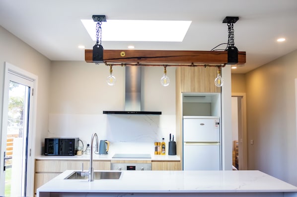 A modern kitchen with a central island, stainless steel appliances, and pendant lighting.