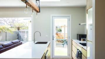 A modern kitchen with a large island, stainless steel appliances, and a view of the backyard.