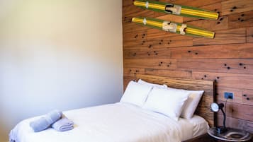 A bedroom with a wooden headboard, a bed with white bedding, and two skis mounted on the wall.