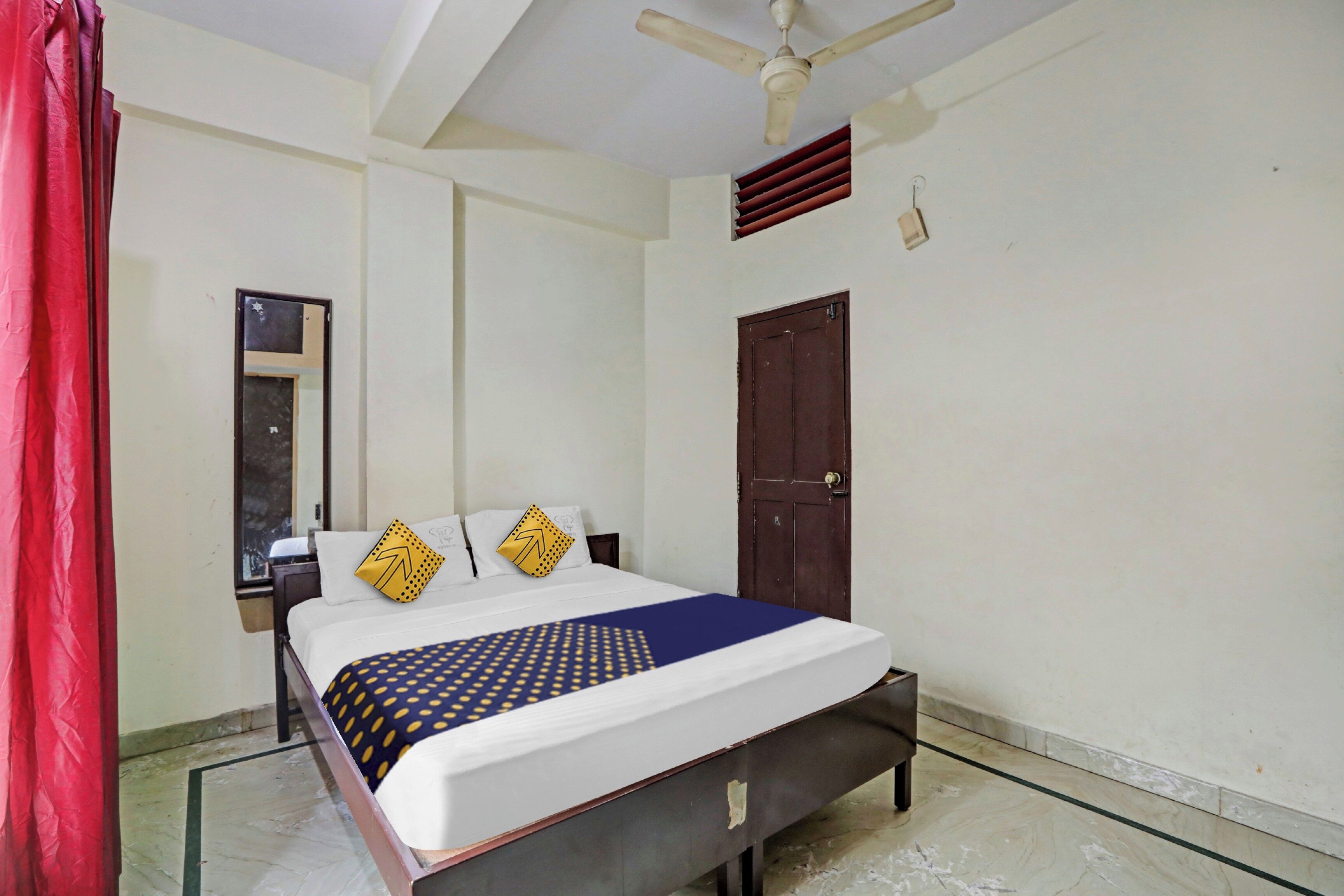 A hotel room with a bed, a nightstand, a mirror, a wardrobe, and a ceiling fan.