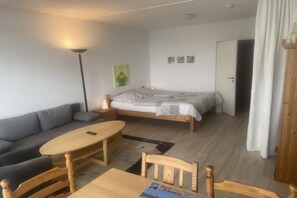 A compact room with a bed, a sofa, a table, and a lamp. - Holiday apartment with 1 bedroom (Burgtiefe auf Fehmarn)