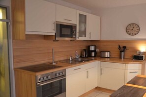 Una cocina moderna con electrodomésticos de acero inoxidable, armarios de madera y un reloj en la pared.
