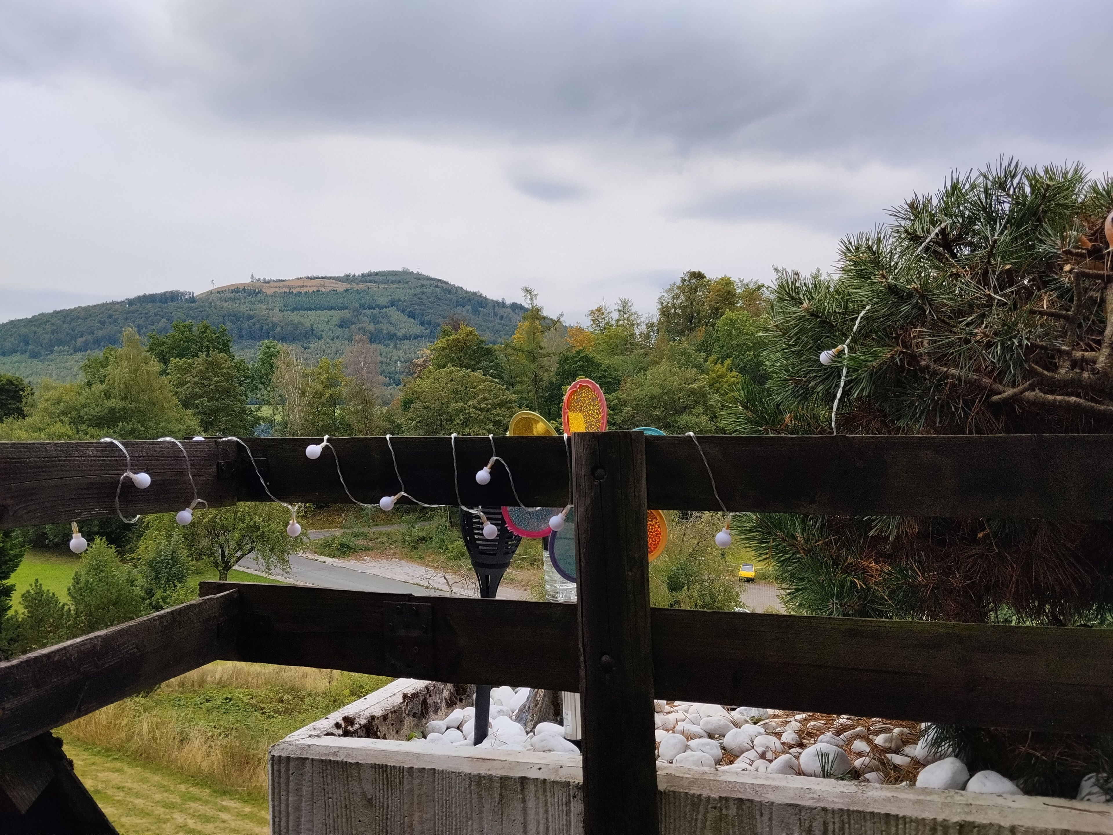 A wooden fence with a view of a green landscape and hills in the background.