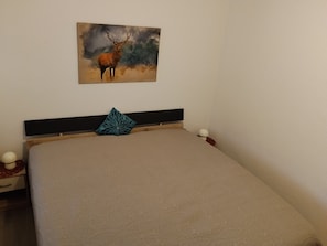 A bedroom with a bed, a pillow, a wall-mounted painting of an elk, and a bedside table with a lamp. - Holiday Apartment 'Olsberg Panorama' with Mountain View and Private Balcony (Olsberg)