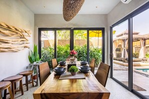 Un comedor con una mesa de madera, tazones negros y sillas.
