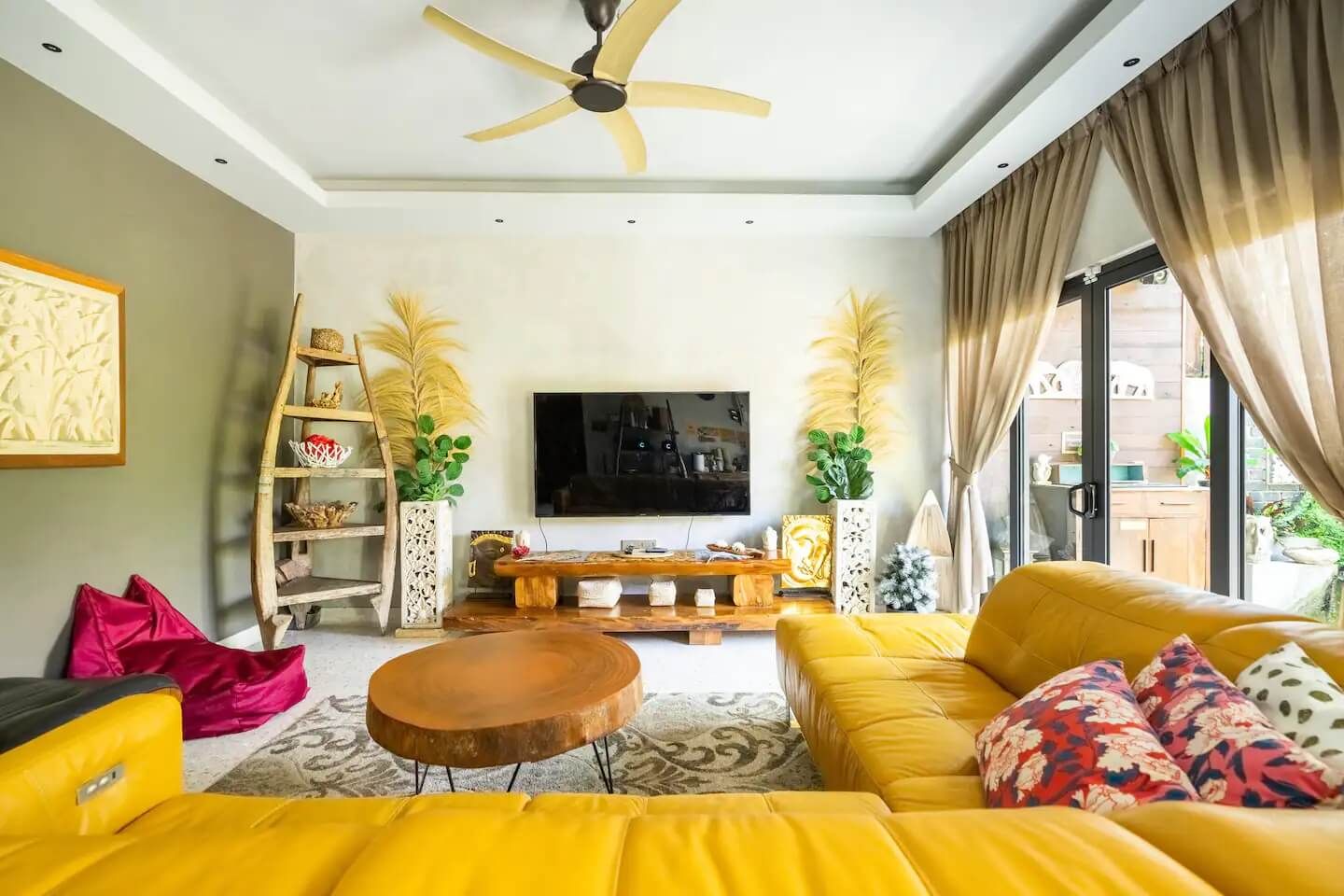 Ein modernes Wohnzimmer mit einem gelben Sofa, einem Holztisch, einem Fernseher und einem Deckenventilator.