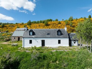 Un bâtiment blanc avec un toit gris, deux petites fenêtres et une porte.