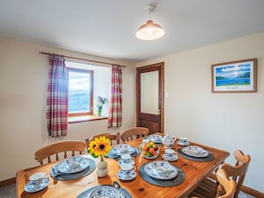 A dining room with a wooden table set for four, a vase with flowers, and a window with curtains. - Wonderful private villa for 5 guests with WIFI, TV, pets allowed and panoramic view (Boleskine)