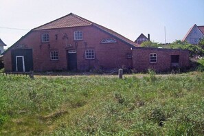A large brick building with a gabled roof, a central door, and multiple windows. - Holiday apartment with 2 bedrooms (Langeoog)