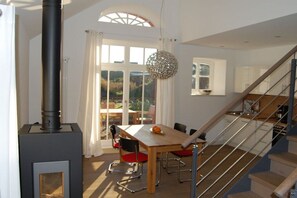 A modern kitchen with a central island, a dining area with chairs, and a staircase leading to an upper level. - Holiday apartment with 2 bedrooms (Langeoog)