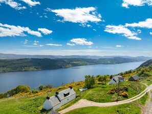 A scenic view of a lake surrounded by hills, with a path leading to a row of white houses. - Wonderful private villa for 5 guests with WIFI, TV, pets allowed and panoramic view (Boleskine)