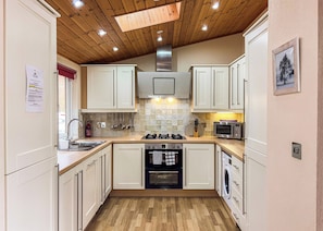 A compact kitchen with white cabinets, a built-in oven, a microwave, and a dishwasher. - 2 bedroom accommodation in Invermoriston (Invermoriston)