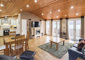 A spacious living area with a wooden ceiling, a dining table, and a sofa. - 2 bedroom accommodation in Invermoriston (Invermoriston)