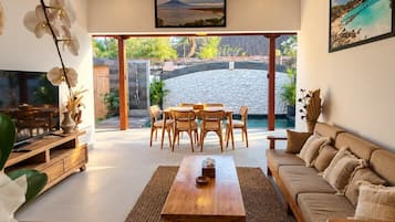 A modern living room with a wooden coffee table, sofa, and dining set.