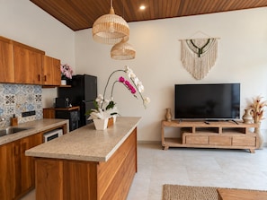 Una cocina moderna con armarios de madera, encimera con motas y una isla central con una orquídea en maceta.