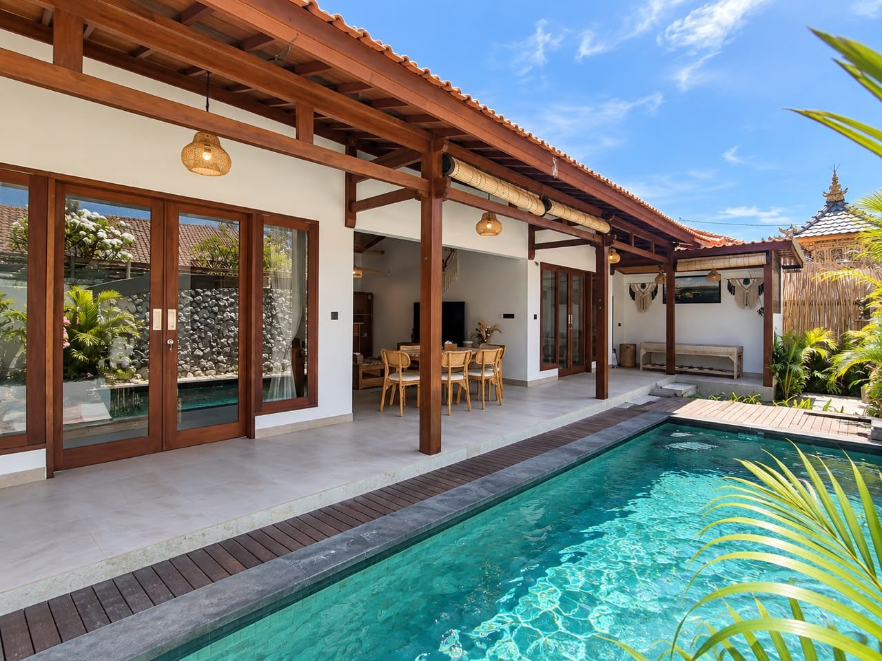 Une maison moderne dotée d’une piscine, d’une pergola en bois et d’un espace repas.
