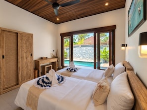 Quarto de hotel com duas camas, teto de madeira, vista para piscina e guarda-roupa de madeira.