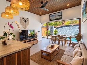 Sala de estar moderna com TV, móveis de madeira e parede de pedra.