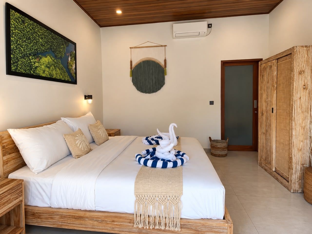 A bedroom with a bed, a macrame wall hanging, a framed picture, and a wooden wardrobe.