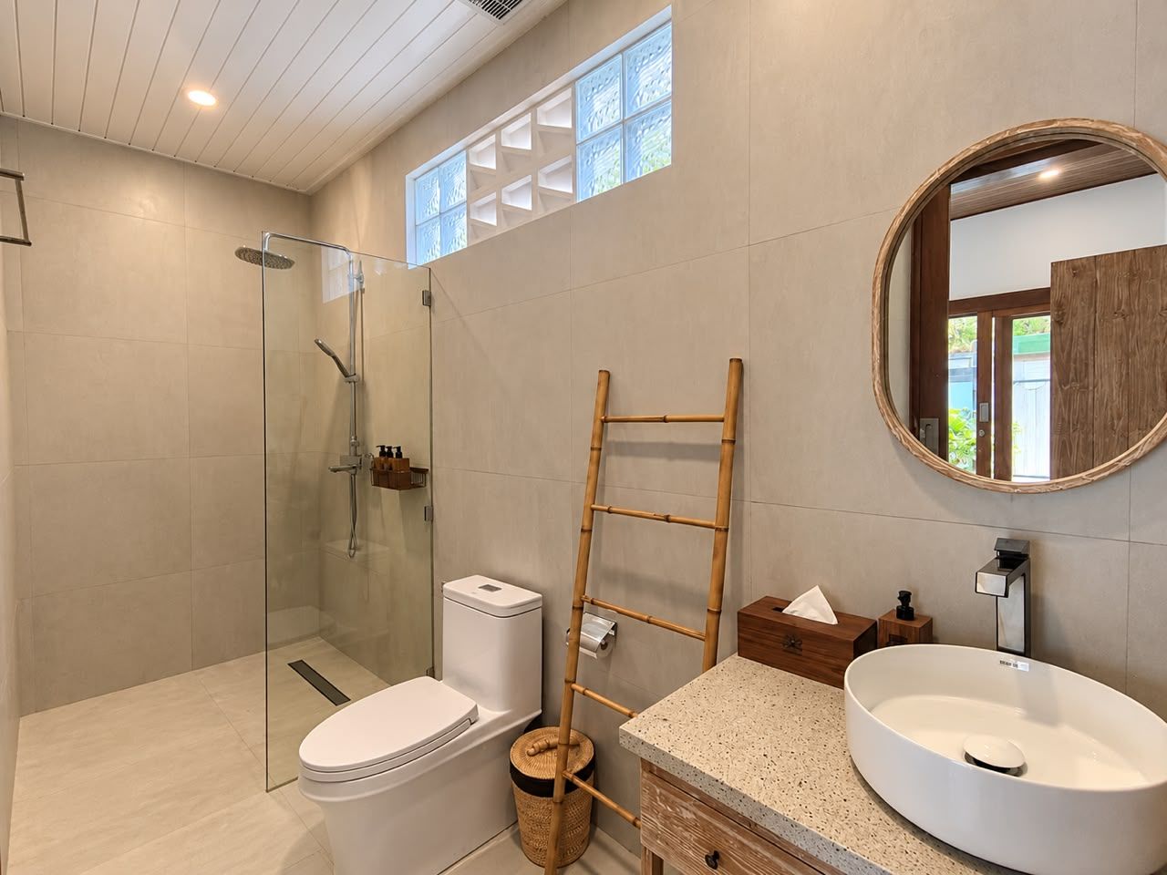 Une salle de bain moderne avec une douche à parois de verre, des toilettes blanches, un lavabo sur pied et une échelle en bois.