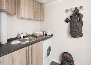 A compact kitchen with a washing machine, a sink, and a drying rack. - 1 bedroom accommodation in Fort Augustus (Fort Augustus)