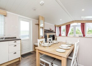 A modern kitchen with a dining table set for four, white cabinetry, and a view of the outdoors. - 1 bedroom accommodation in Fort Augustus (Fort Augustus)