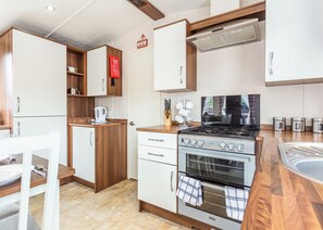A modern kitchen with a gas stove, oven, and white cabinetry. - The Ness, Woodland Retreat (Fort Augustus)