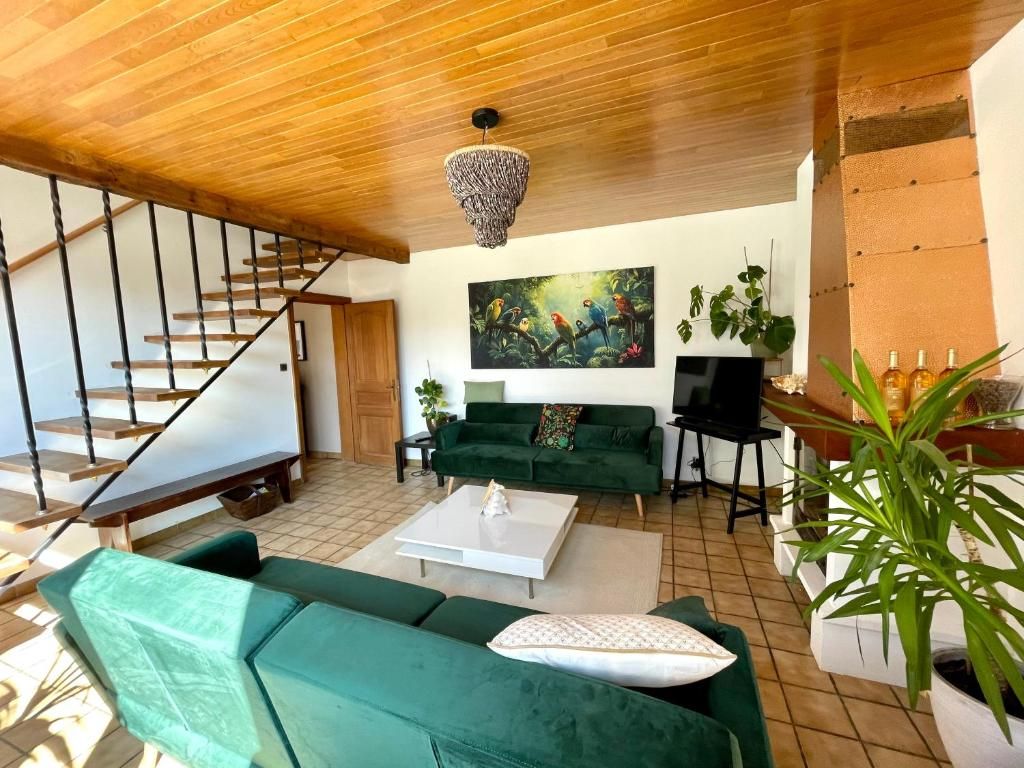 A spacious living area with a staircase, a green sofa, a white coffee table, and a painting of parrots.