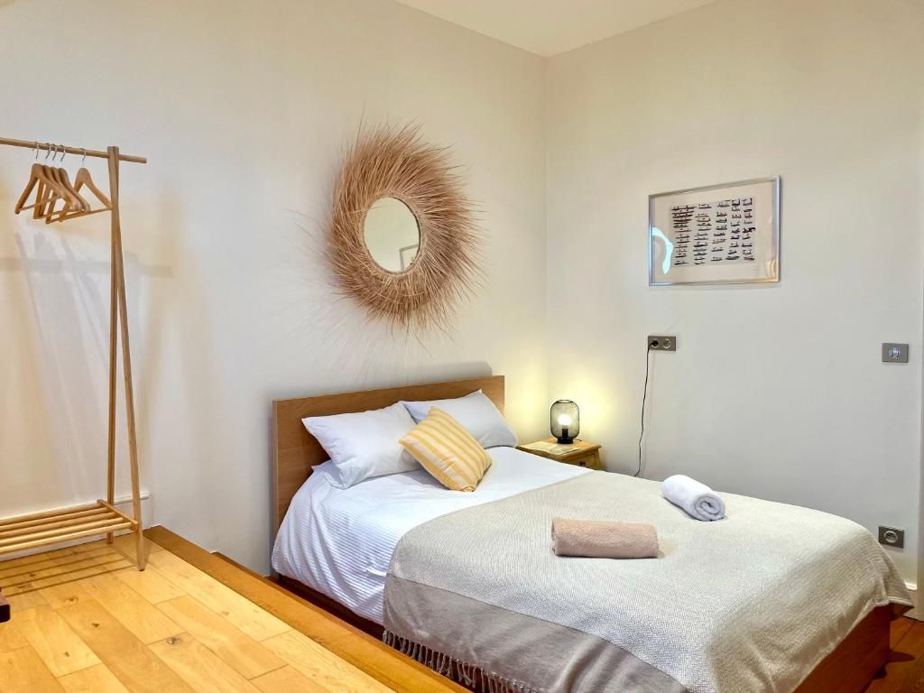 Een netjes opgemaakt bed met hoofdeinde, een bedlampje en een wandspiegel.