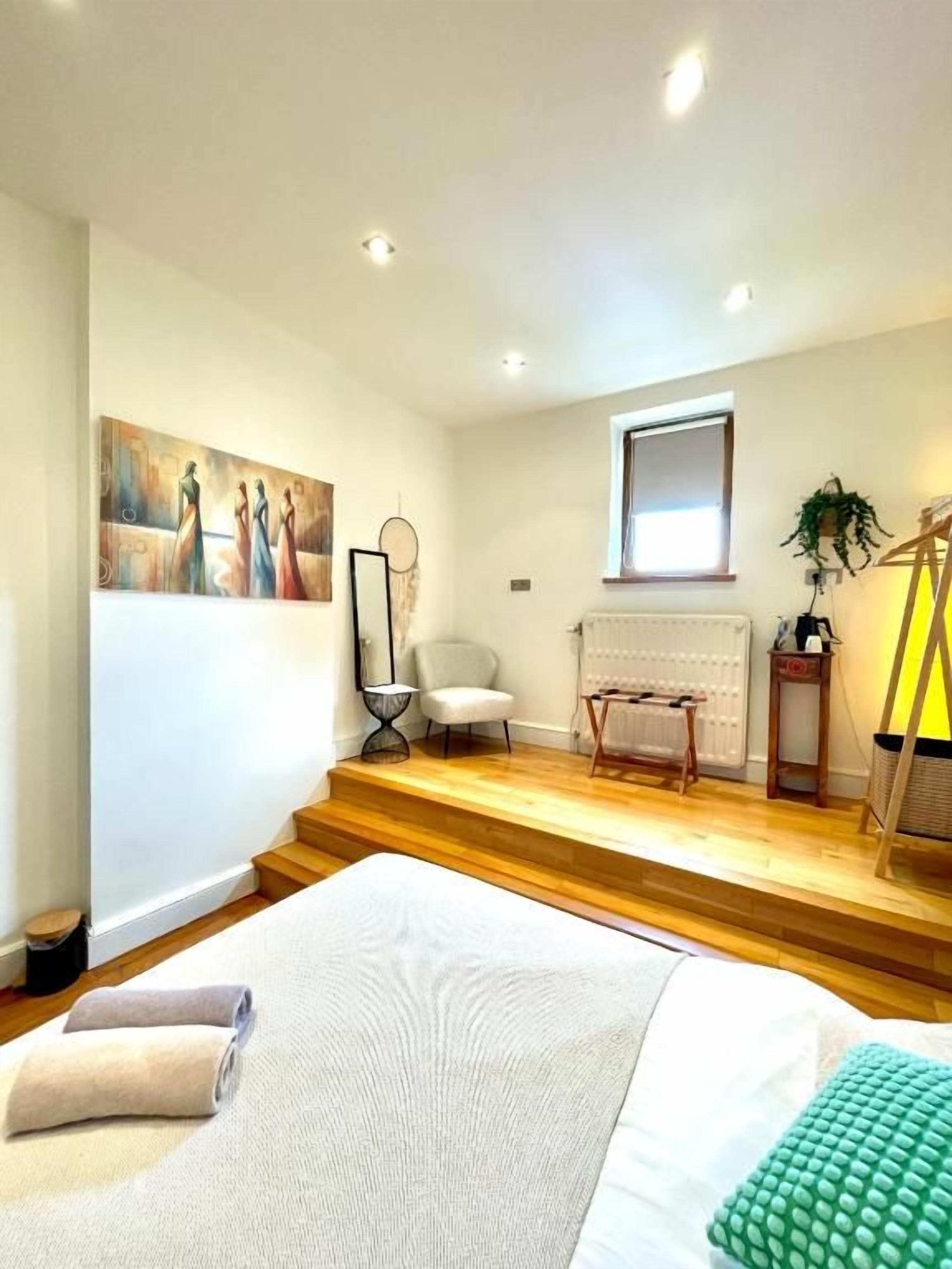 Habitación de hotel con cama, una silla, una mesita, un cuadro en la pared y una ventana.