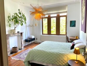 A bedroom with a bed, a window, a plant, and a lamp.