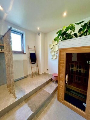 A room with a wooden staircase, a window, a plant wall, and a door with a glass panel.
