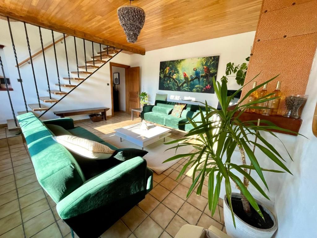 Un salon moderne avec un canapé vert, une table basse, un escalier et un grand tableau.
