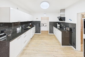 Een moderne keuken met witte kasten, zwarte aanrechtbladen en een centraal eiland.