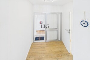 A hallway with a wooden floor, a white door with a window, and a wall-mounted decoration. - Holiday apartment with 1 bedroom (Langeoog)