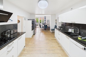 A modern kitchen with white cabinets, a black countertop, and a wooden floor. - Holiday apartment with 1 bedroom (Langeoog)