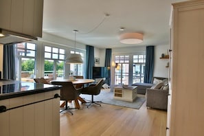 A modern living room with a dining area, large windows, and a view of the outdoors. - Holiday apartment Inselherz (Wangerooge)