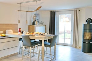 A modern kitchen with a dining table, chairs, and a built-in oven. - Thatched house "Blinkfor" (Zierow)