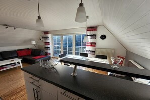 A modern kitchen with a black countertop, a dining table, and a hanging light fixture. - Holiday apartment in Dangast with balcony (Dangast)