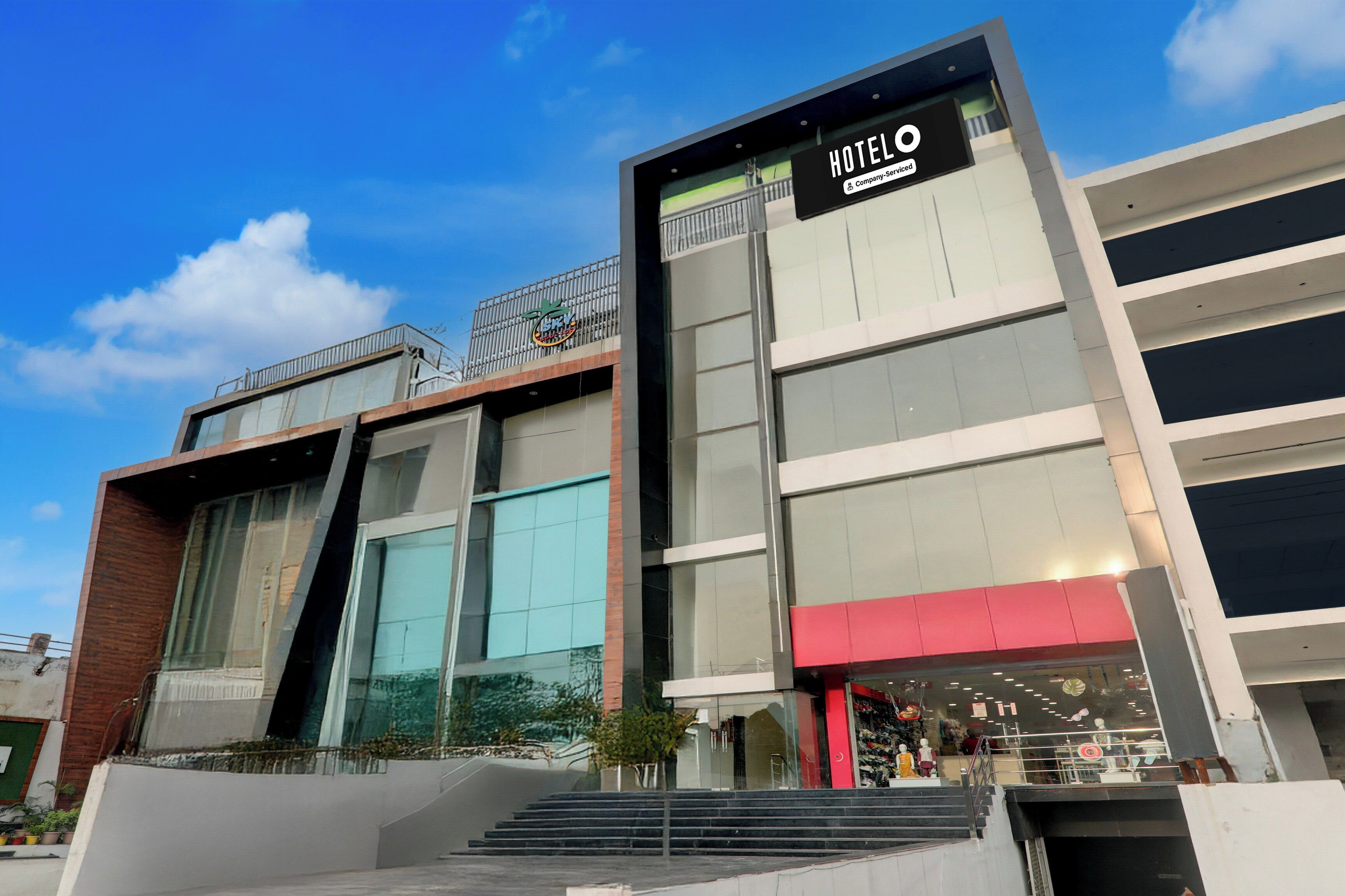 A modern hotel building with a prominent sign for 'HOTEL O' and a visible entrance with steps leading up to it.