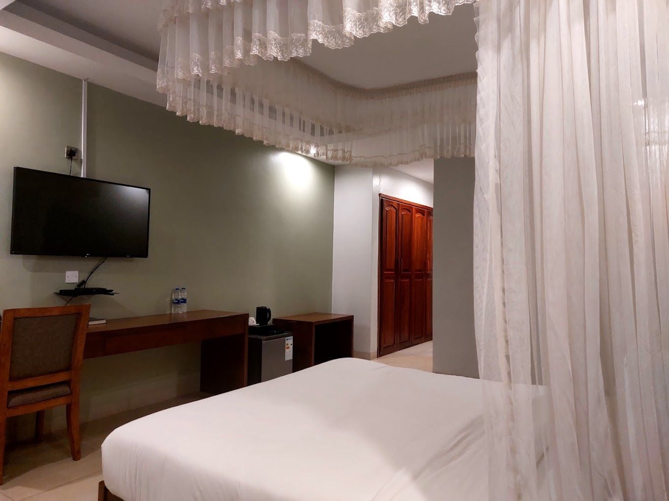 Una habitación de hotel con cama, escritorio, televisor y armario.