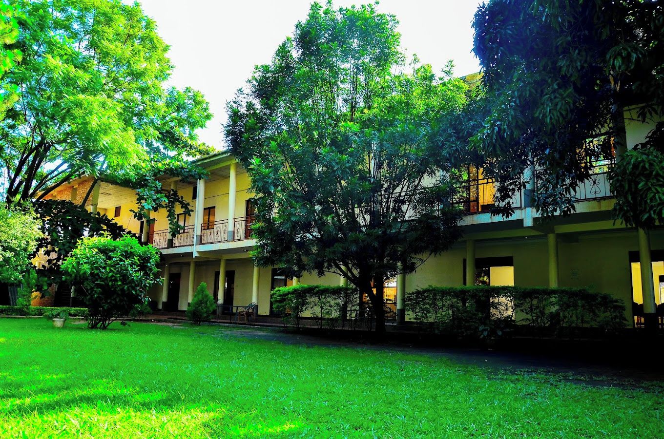 A building with multiple floors, balconies, and a well-maintained lawn.