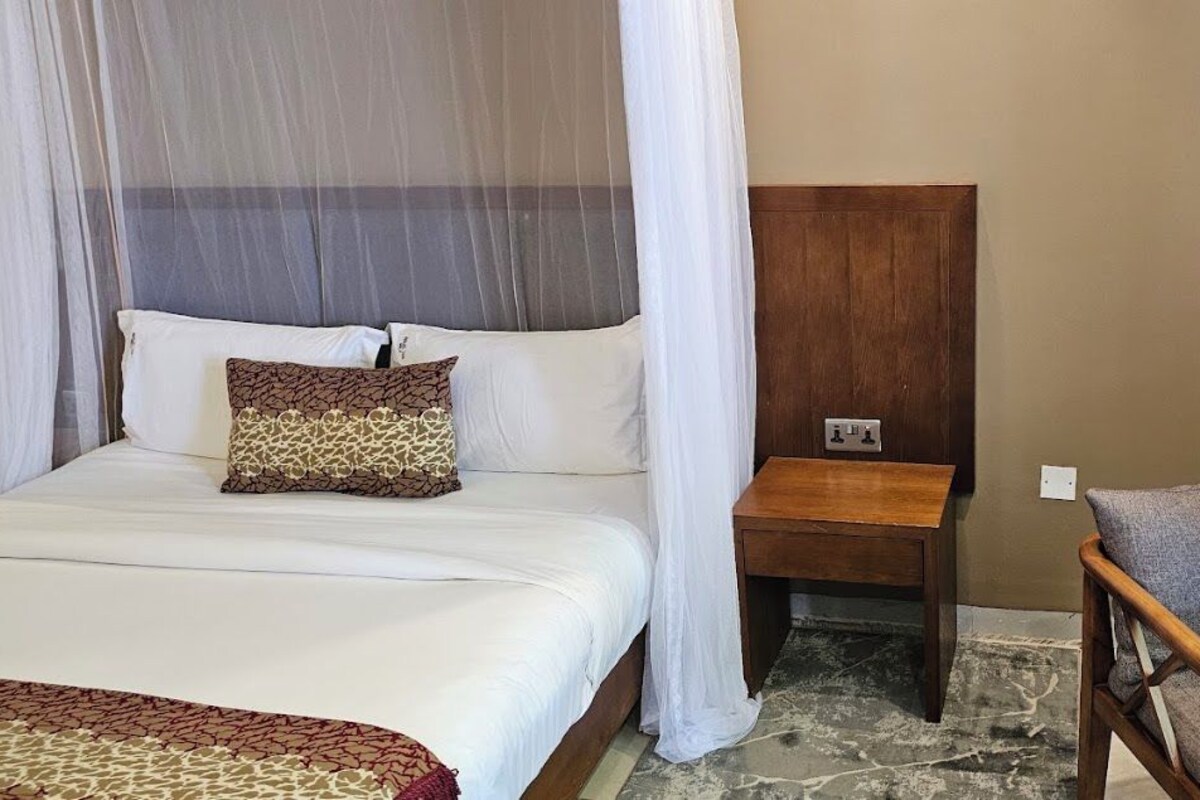 Una habitación de hotel con una cama, una mesita de noche, una silla y un buró.