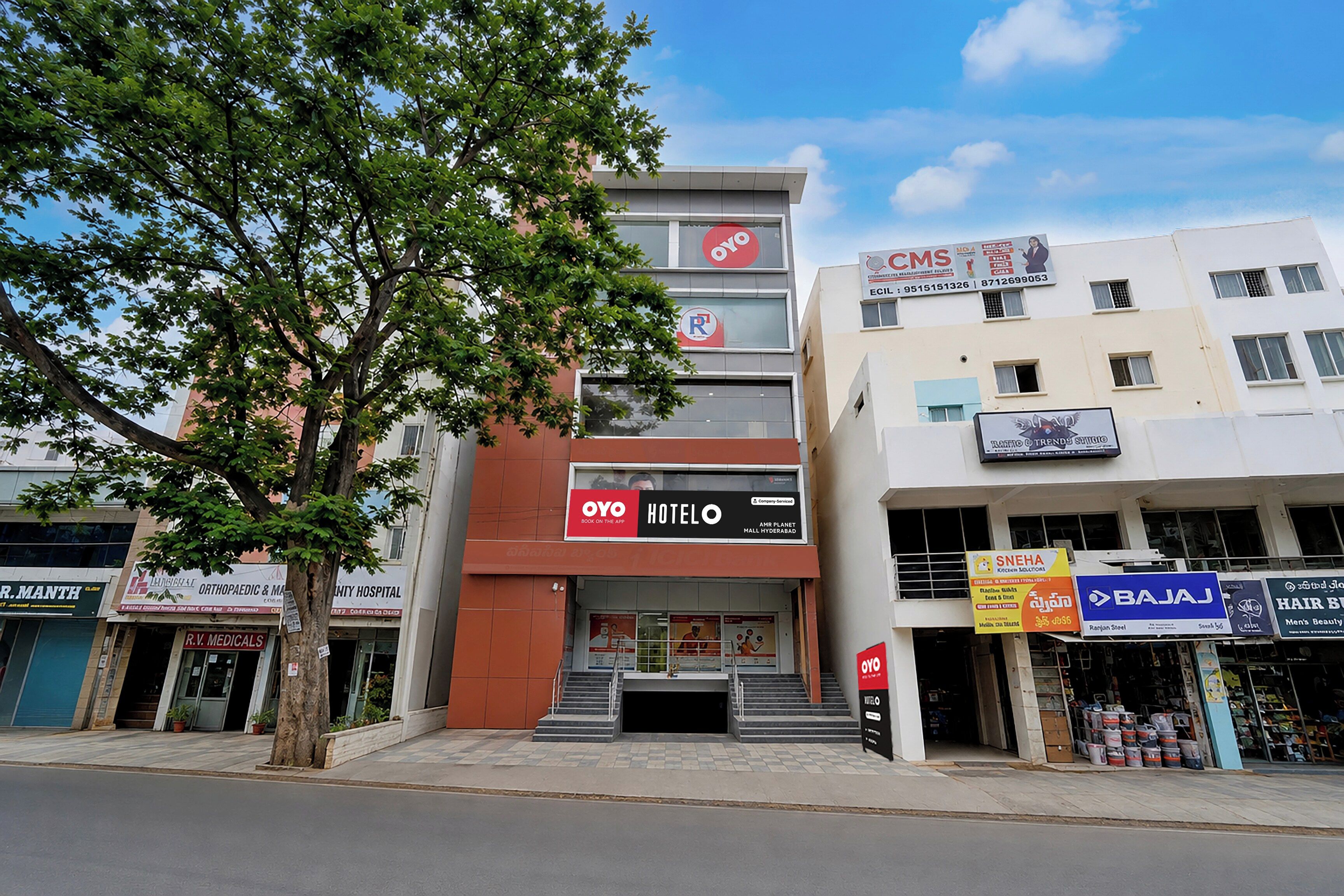 Un hôtel à la façade rouge et blanche, avec plusieurs étages et un escalier menant à l’entrée.