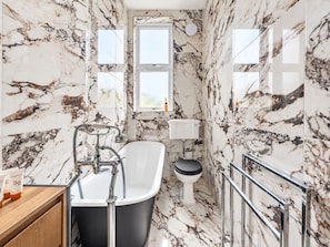 A bathroom with a freestanding bathtub, a toilet, and a window. - Lovely Flat near Royal Botanic Garden (Edinburgh)