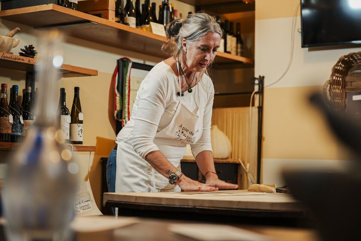 A person working at a table in a room with shelves of wine bottles.