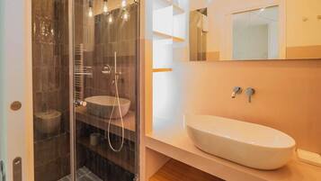 Une salle de bain moderne avec une douche en verre, un lavabo blanc et un miroir au-dessus du lavabo.