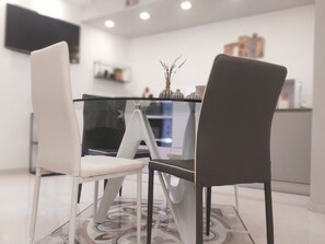 Een moderne eethoek met een glazen tafel, twee stoelen en een decoratieve vaas.