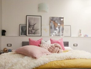 Une chambre à coucher avec un lit, des oreillers et des œuvres d’art murales.